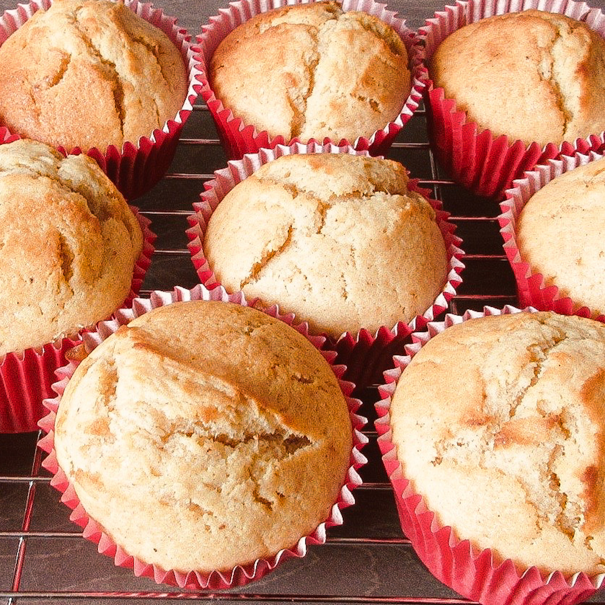 Banana muffins in red muffin cases on a cooling rack.