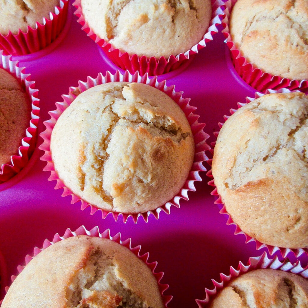 banana muffins in red muffin cases in a pink flat cupcake holder.