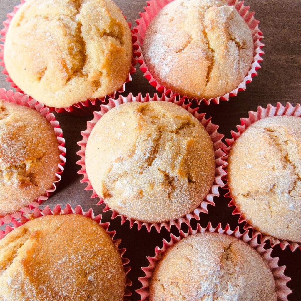 Top view of banana muffins in red muffin cases and dusted with icing sugar.