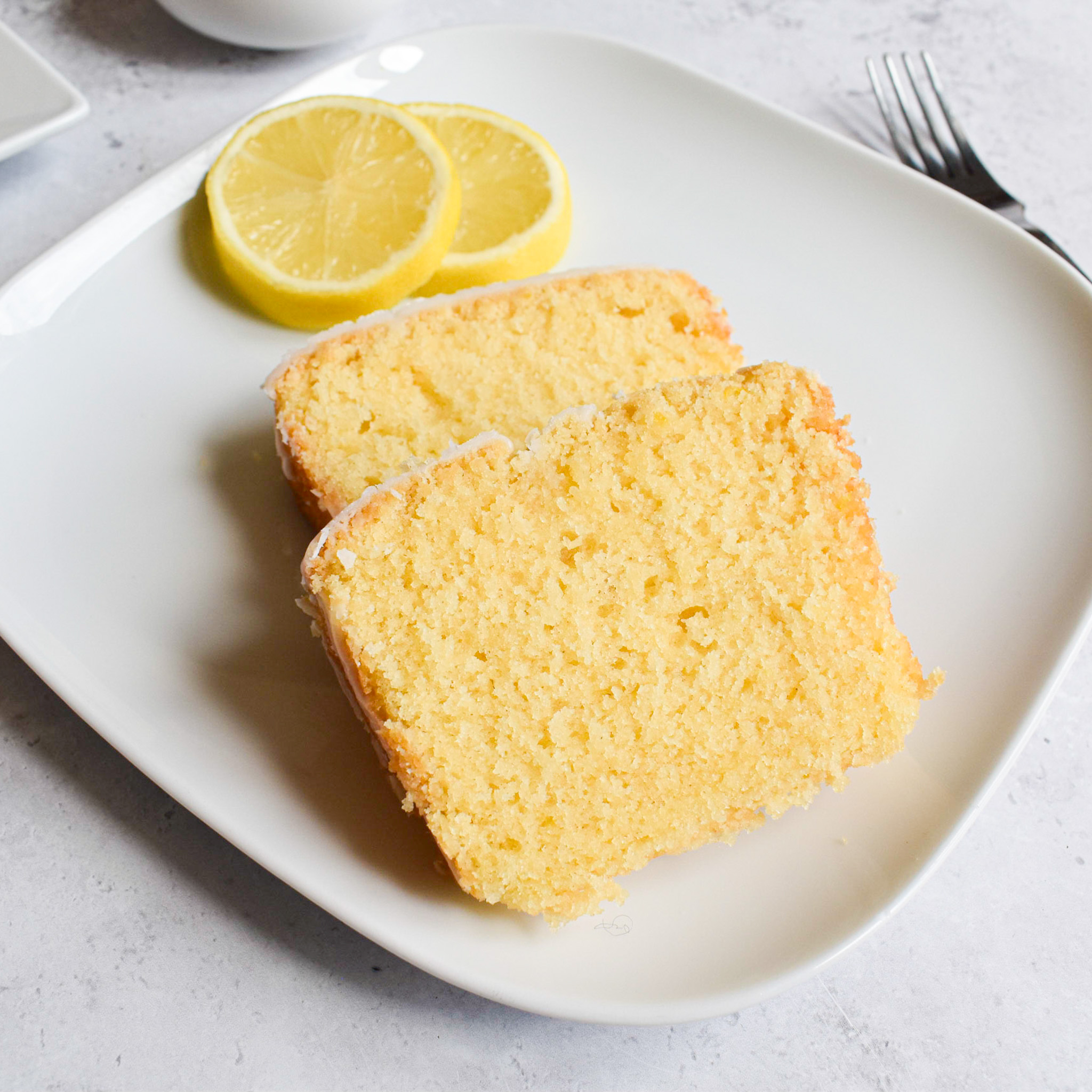 2 slices of lemon drizzle loaf cake and sliced lemons.